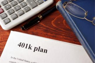 401k plan paper with a calculator and a book next to it