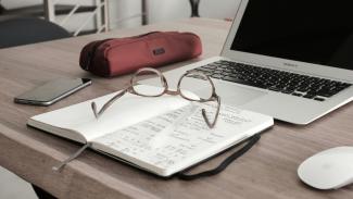 eyeglasses on book beside laptop by Dan Dimmock courtesy of Unsplash.