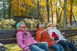 three people sitting on a bench in a park by Vitolda Klein courtesy of Unsplash.