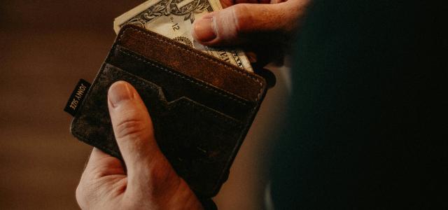 person getting 1 U.S. dollar banknote in wallet by Allef Vinicius courtesy of Unsplash.